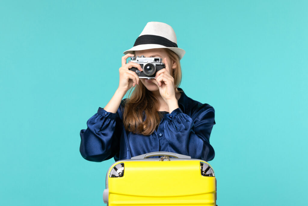 front-view-young-woman-holding-camera-taking-photos-blue-background-woman-journey-sea-travelling-voyage-plane