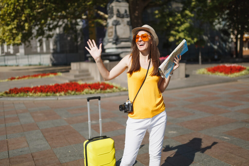 traveler-tourist-woman-orange-heart-glasses-with-suitcase-city-map-retro-vintage-photo-camera-spreading-hands-city-outdoor-girl-traveling-abroad-weekend-getaway-tourism-journey-lifestyle